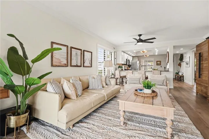 Living room with ornamental molding, wood finished floors, and a ceiling fan