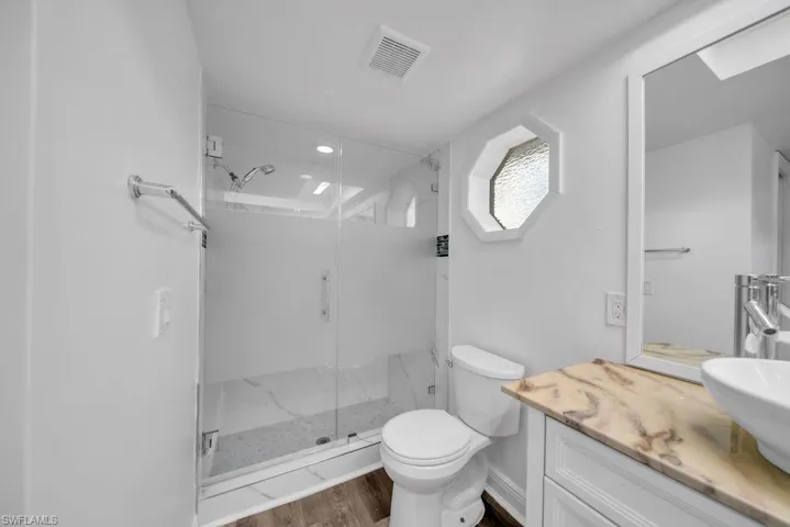 Full bath with vanity, a shower stall, and dark wood finished floors