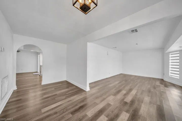 Unfurnished room featuring wood finished floors and arched walkways