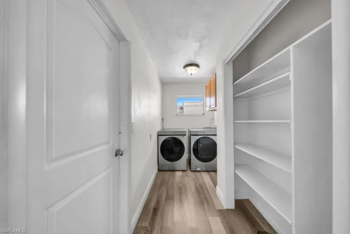 Laundry area with light wood-style floors, separate washer and dryer, and cabinet space