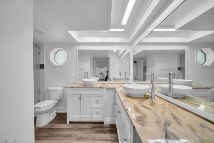 Full bathroom featuring double vanity, light wood-type flooring, and ornamental molding