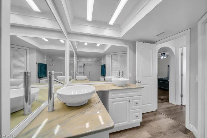 Full bath with a shower stall, vanity, light wood-style flooring, a closet, and a ceiling fan