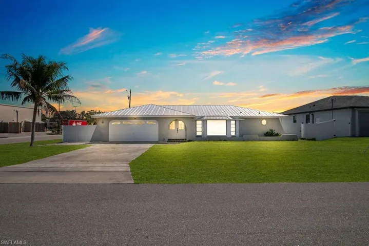 View of front of home with stucco siding, driveway, a garage, and a yard