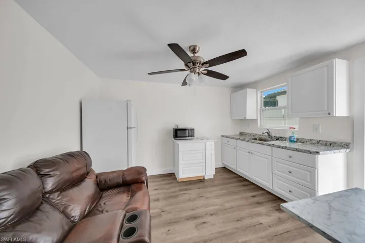 Kitchen featuring light countertops, freestanding refrigerator, white cabinetry, light wood-style flooring, and a ceiling fan