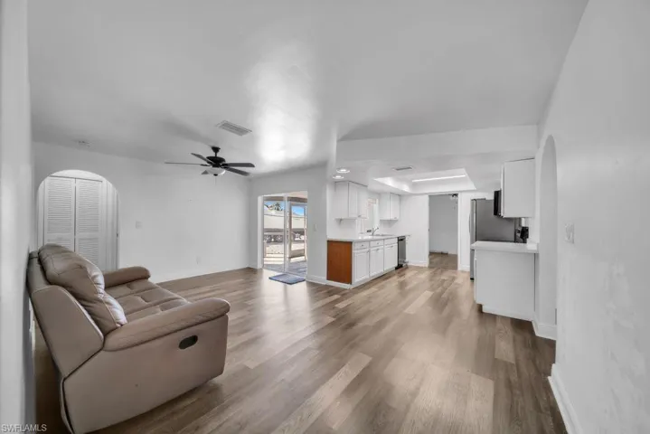 Living room with arched walkways, dark wood-style floors, and a ceiling fan