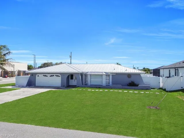 View of front facade with a garage, concrete driveway, stucco siding, a metal roof, and a gate