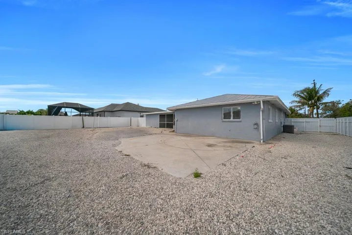 Back of property with a fenced backyard, a metal roof, and a patio