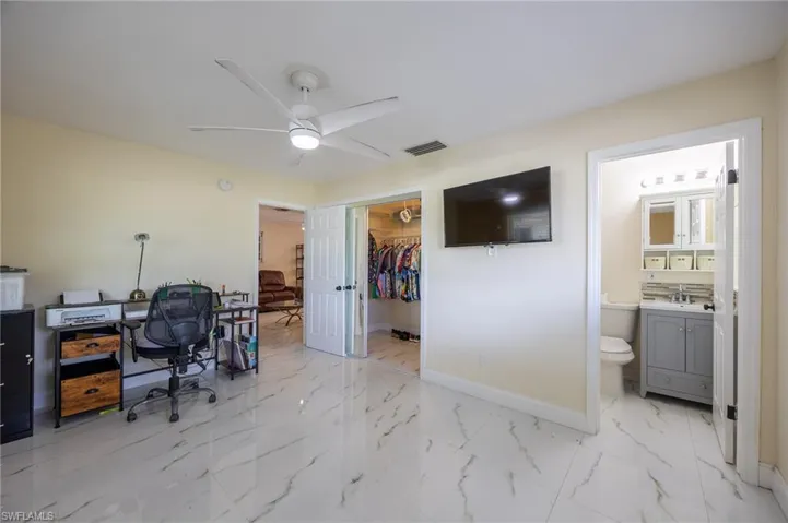 Office area featuring ceiling fan, a sink, visible vents, baseboards, and marble finish floor