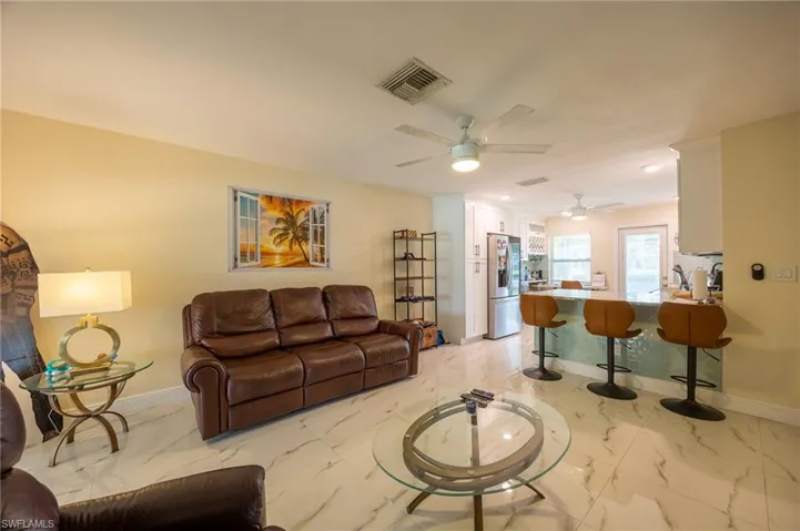 Living room with marble finish floor, baseboards, visible vents, and ceiling fan