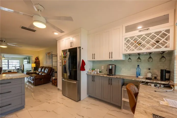 Kitchen featuring ceiling fan, marble finish floor, white cabinetry, and stainless steel fridge with ice dispenser