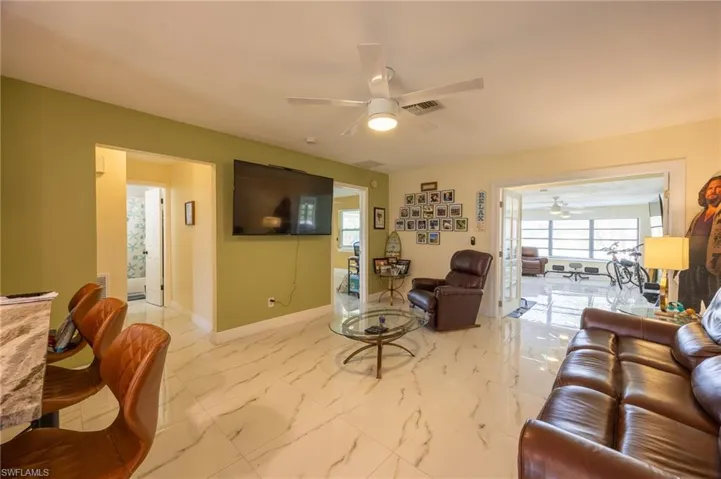 Living room with baseboards, marble finish floor, visible vents, and a ceiling fan