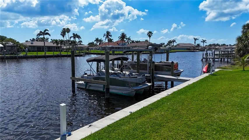View of dock featuring a water view, a lawn, and boat lift