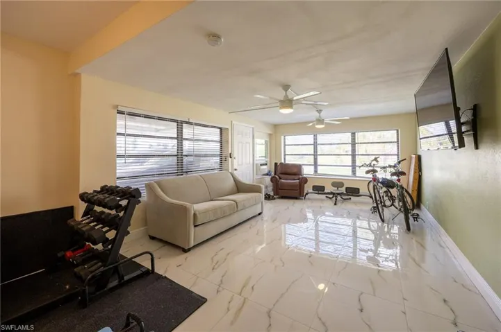 Living room featuring a ceiling fan, marble finish floor, and baseboards