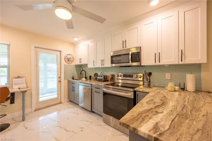 Kitchen featuring light stone countertops, marble finish floor, stainless steel appliances, and a sink