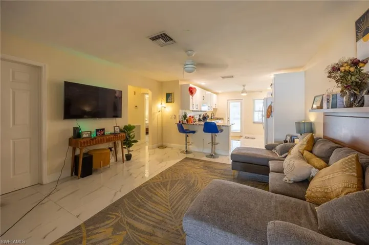 Living room featuring marble finish floor, visible vents, ceiling fan, and baseboards