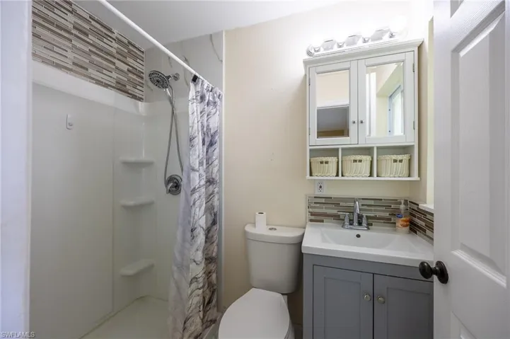 Full bath with toilet, tasteful backsplash, vanity, and a shower with shower curtain