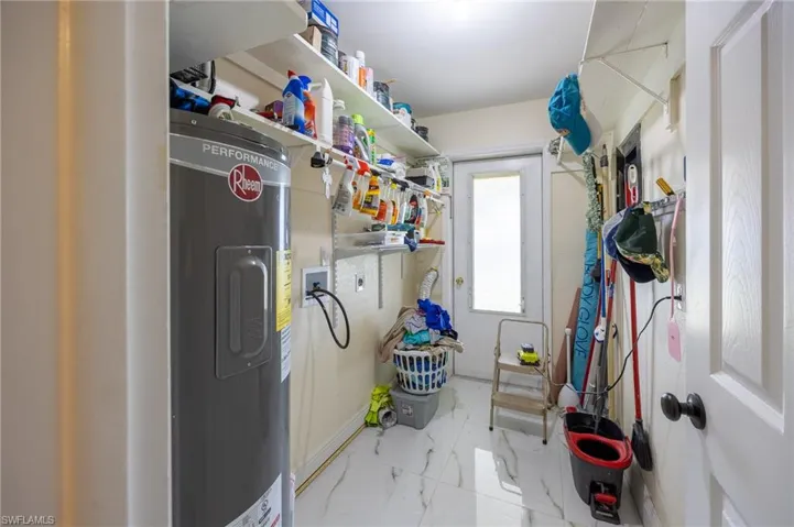 Clothes washing area with water heater, marble finish floor, hookup for a washing machine, and laundry area