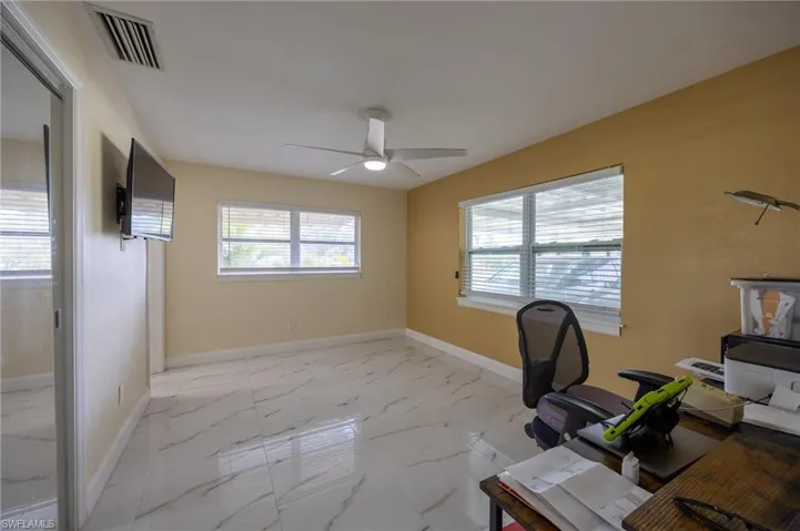 Unfurnished office with marble finish floor, visible vents, and a healthy amount of sunlight