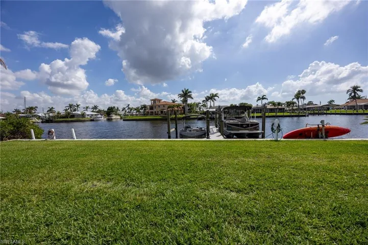 View of dock with a water view, a yard, and boat lift