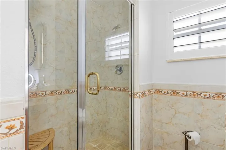 Full bathroom featuring a shower stall and tile walls