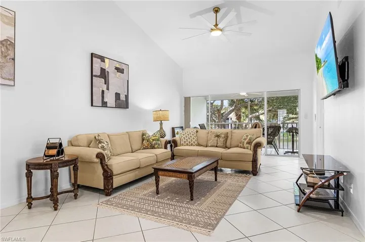Living room with high vaulted ceiling, light tile patterned floors, and a ceiling fan