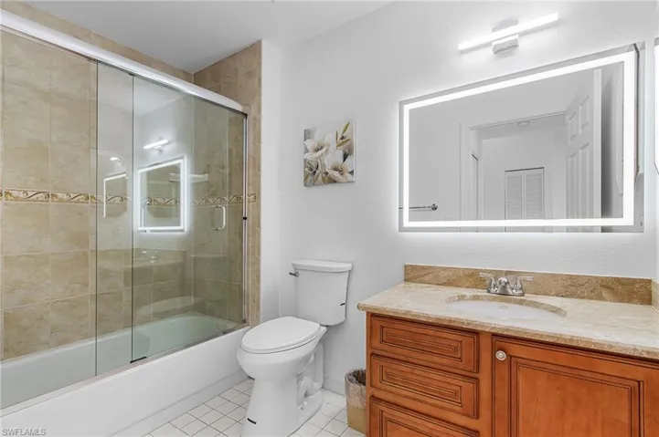 Full bath with tile patterned flooring, vanity, and enclosed tub / shower combo