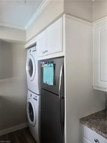 Stackable washer and dryer combination beside a stainless steel refrigerator
