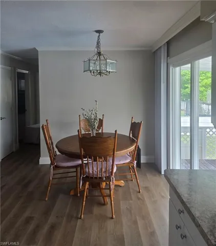 Dining area featuring wood-finish flooring, neutral wall tones, and crown molding