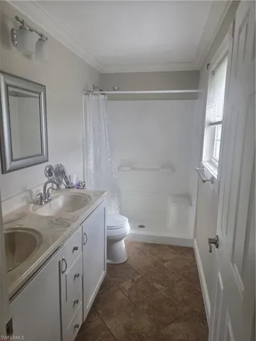 Bathroom featuring a dual-sink vanity with an integrated countertop, white cabinetry, and a shower/tub combination