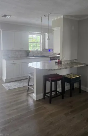 Kitchen featuring white cabinetry, a light-colored countertop, and a matching backsplash