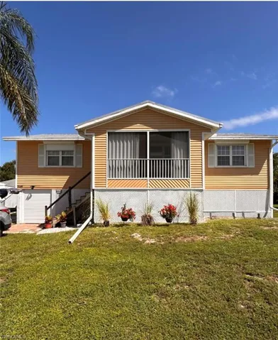Exterior featuring light orange siding, a screened-in porch with white railings, and white window shutters