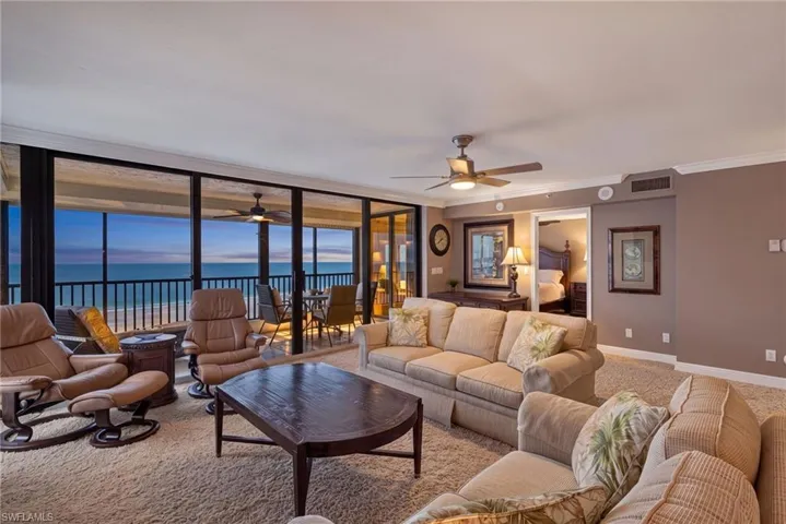 Expansive living area with full-height glass doors, balcony access, and a ceiling fan
