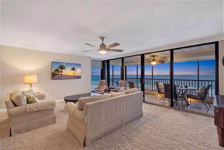 Expansive glass sliding doors with balcony access, ceiling fan with integrated lighting, and neutral wall tones