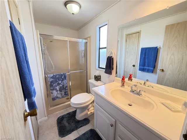 Full bath featuring a shower stall, vanity, and light tile patterned flooring