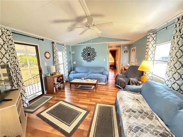 Living area featuring healthy amount of natural light, light wood-style floors, lofted ceiling, and ceiling fan