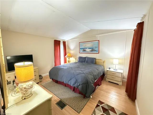 Bedroom with lofted ceiling and wood-type flooring