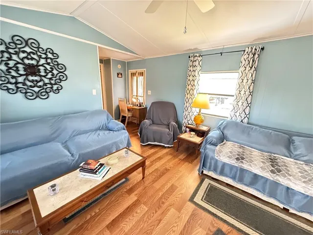 Living room with vaulted ceiling, wood finished floors, and ceiling fan