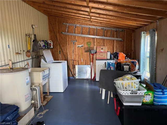 Miscellaneous room featuring concrete floors, water heater, and independent washer and dryer