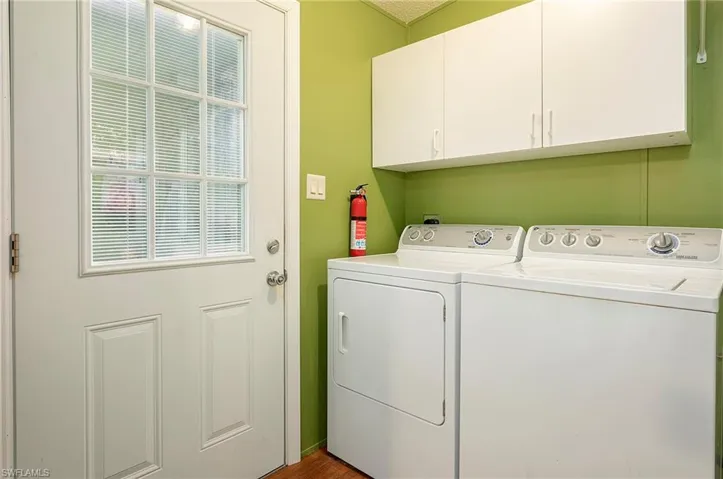 Laundry room with washing machine and clothes dryer, light hardwood / wood-style flooring, and cabinets