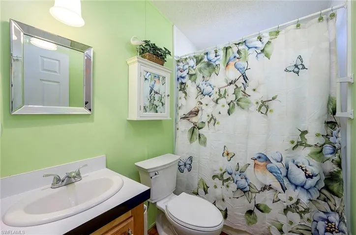 Bathroom featuring vanity, a shower with shower curtain, a textured ceiling, and toilet