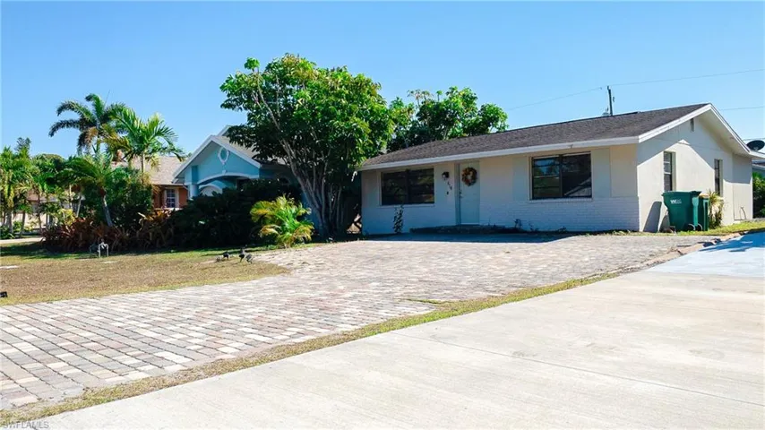 Ranch-style house featuring brick siding, a front lawn, and stucco siding