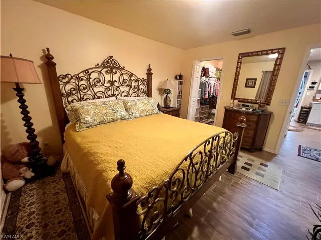 Bedroom with a spacious closet, dark wood-type flooring, and a closet