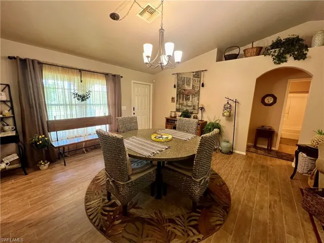 Dining room featuring light hardwood / wood-style floors, vaulted ceiling, and a notable chandelier