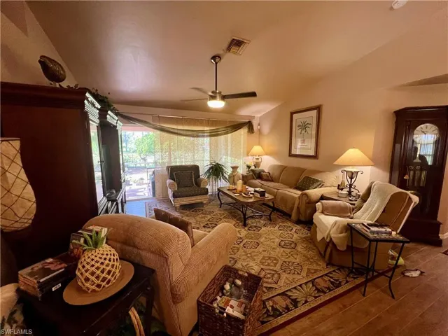 Living room featuring lofted ceiling, hardwood / wood-style floors, and ceiling fan
