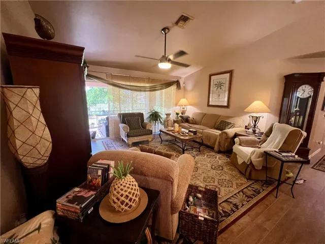 Living room with hardwood / wood-style flooring, lofted ceiling, and ceiling fan
