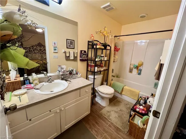 Full bathroom with shower / tub combo with curtain, vanity, hardwood / wood-style flooring, and toilet