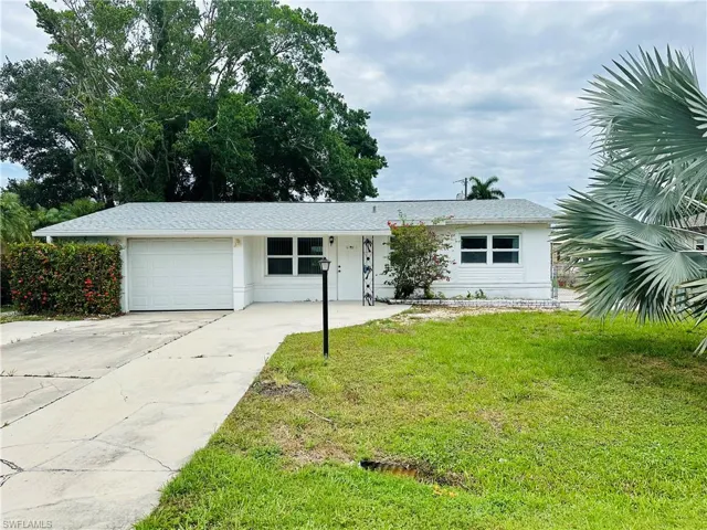 Single story home with a garage and a front lawn