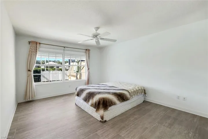Bedroom featuring a ceiling fan, wood finished floors, and a textured ceiling