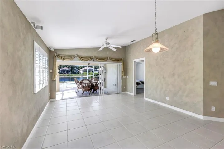 Spare room featuring a ceiling fan, vaulted ceiling, and light tile patterned floors
