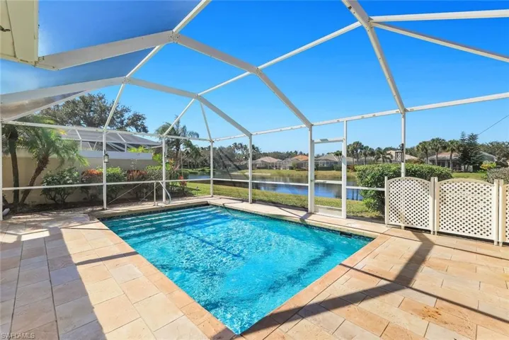 Swimming pool featuring glass enclosure, a water view, a sunroom, a patio, and a residential view